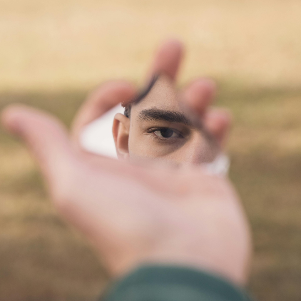 Man holding shard of glass only reflecting his eye